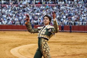 Andrés Roca Rey recorre el ruedo de la Maestranza con las dos orejas de su primer toro, con la Puerta del Príncipe entreabierta