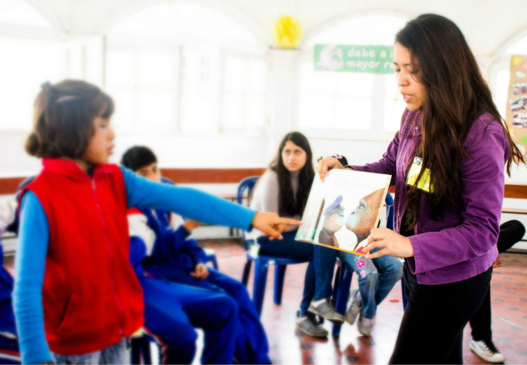 Voluntaria a cargo del LIVA: Alexandra Becerra le muestra las imágenes del cuento a los niños(as).